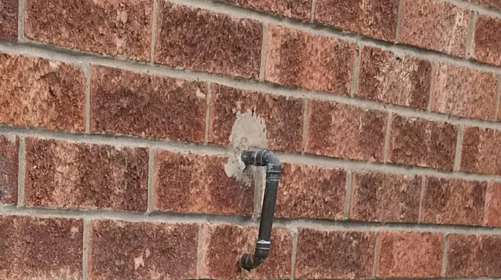 Pressure relief valve discharge pipe through an outside brick wall